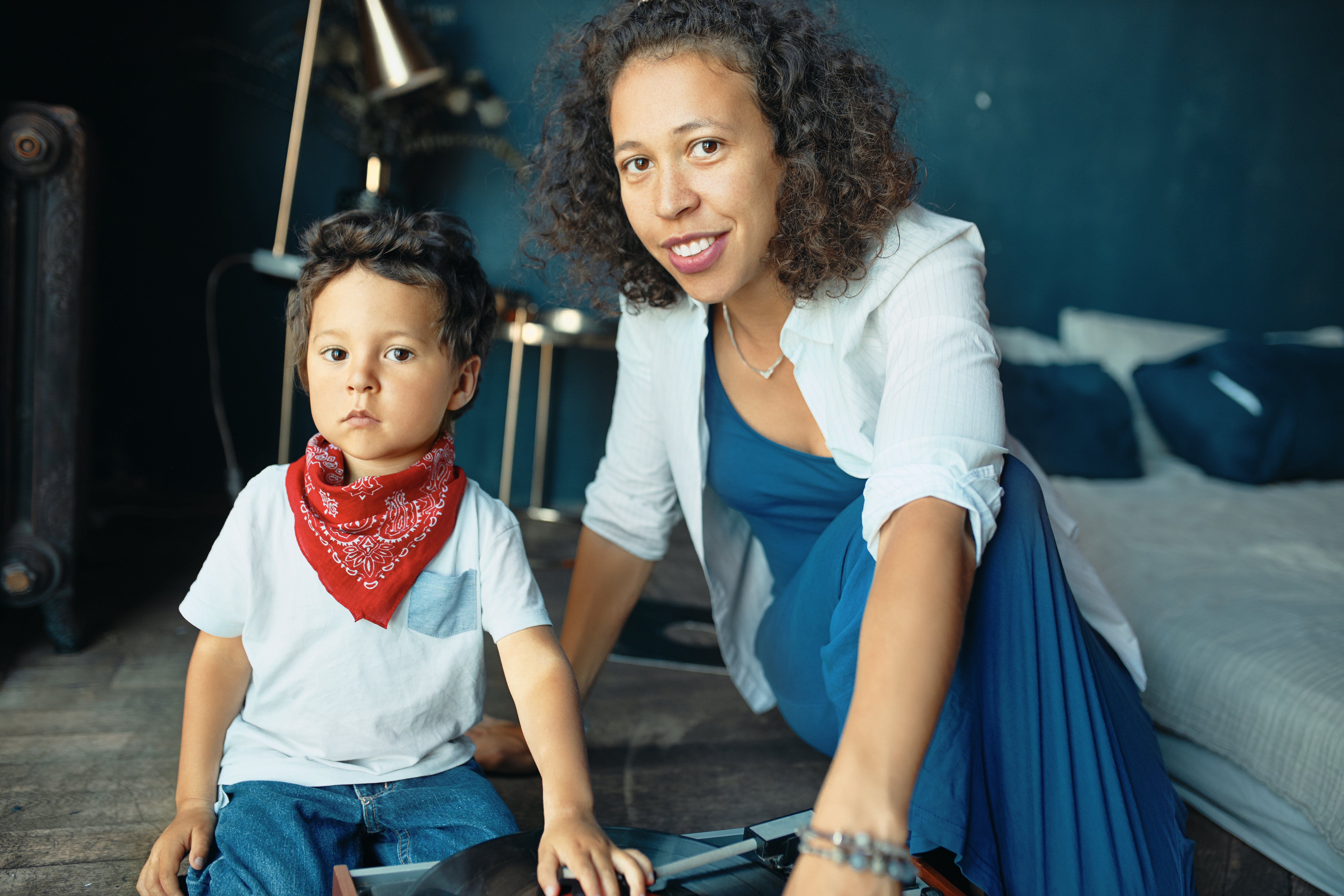 portrait-of-serious-little-boy-with-chubby-cheeks-and-red-kerchief-around-his-neck-sitting-on-floor-with-mom